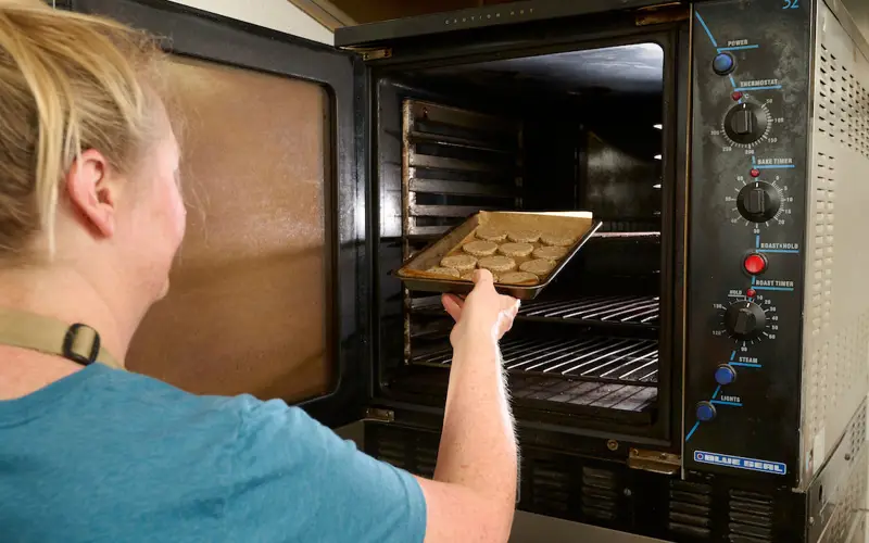 Donna putting crackers into the oven 