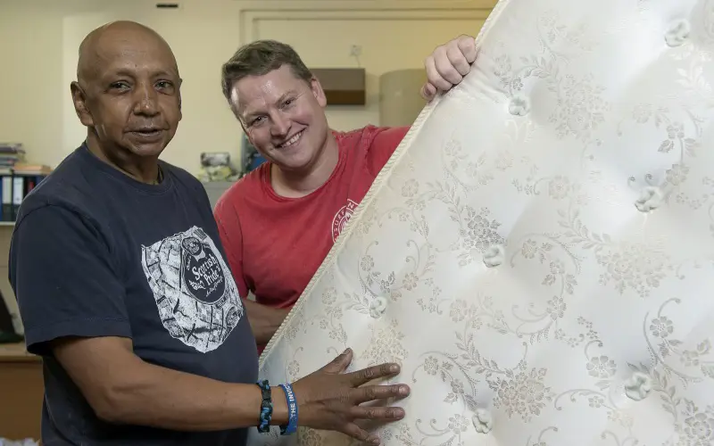 two people holding a mattress in Blindcraft workshop