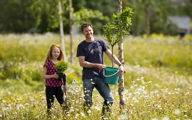 Young man and girl holding tree in field ready for planting 