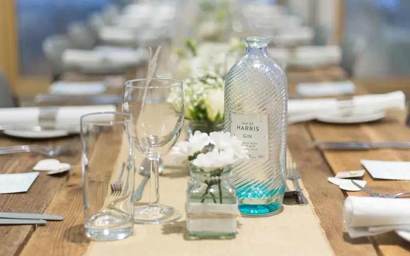 close up of table set with cutlery and glasses and bottle of Harris gin
