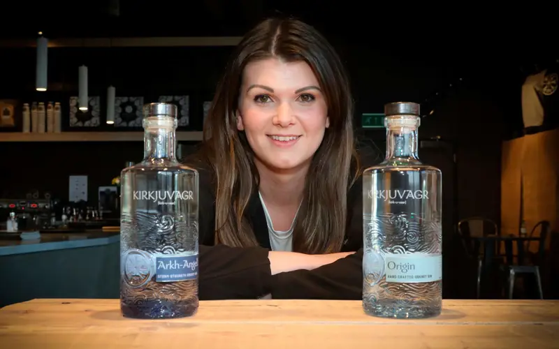 Woman in the middle of two crafted clear bottles of gin