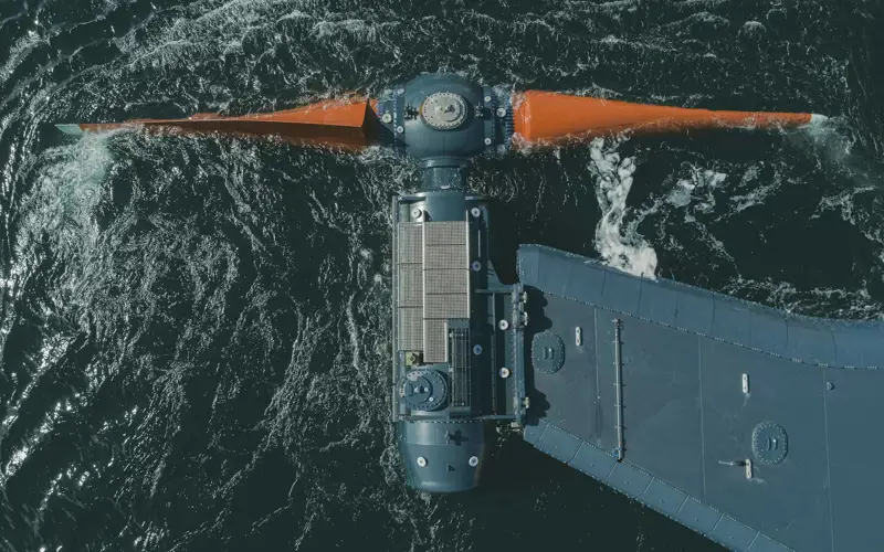 Orbital turbine, t-shaped with large orange blades at the front in the dark ocean offshore of Orkney 